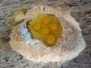 A fountain of pasta dough ingredients - the egg mixture is trying to escape!